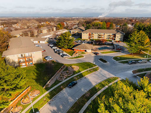 A parking lot is surrounded by trees and buildings at Rosemont Place Apartments, Des Moines