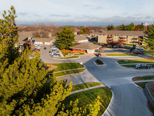 A parking lot with cars and a building in the background. at Rosemont Place Apartments, Des Moines, IA
