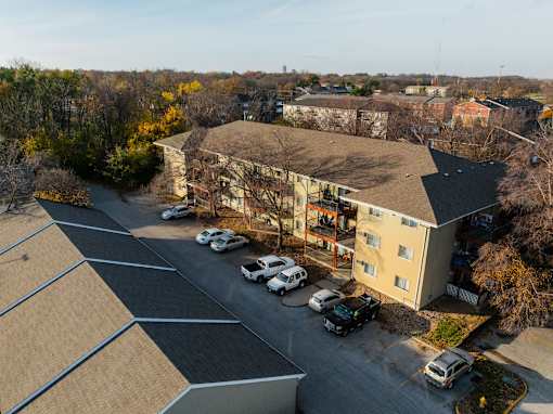 A parking lot with cars and a building in the background. at Rosemont Place Apartments, Des Moines, IA, 50320