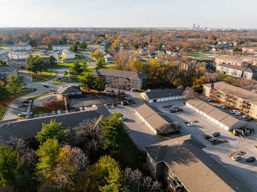 A large parking lot is surrounded by buildings and trees at Rosemont Place Apartments, Des Moines