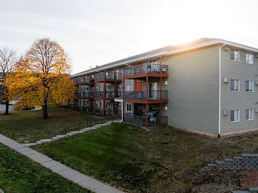 A building with a balcony and a tree with yellow leaves at Rosemont Place Apartments, Iowa, 50320