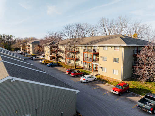 A parking lot with cars and apartment buildings in the background. at Rosemont Place Apartments, Iowa