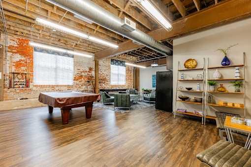 A room with a wooden floor and a brick wall at Spaulding Lofts Apartments, Iowa, 50112