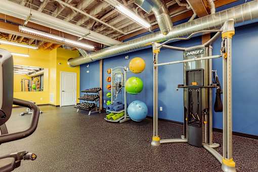 A gym with a variety of equipment including a weight machine and a bench press at Spaulding Lofts Apartments, IA, 50112