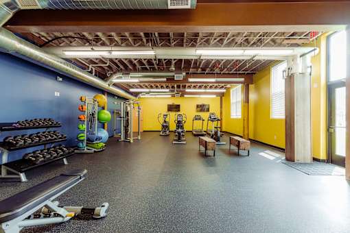 A gym with a variety of equipment including weights and exercise machines at Spaulding Lofts Apartments, IA, 50112