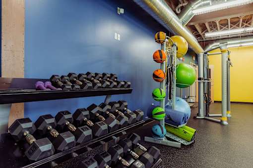 A gym with a rack of black dumbbells and a green exercise ball at Spaulding Lofts Apartments, Grinnell