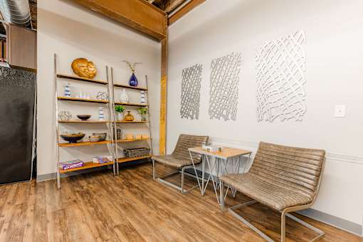 A kitchen with a refrigerator, a table with two chairs, and shelves with various items at Spaulding Lofts Apartments, Iowa