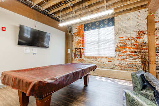 A room with a red table and a brick wall at Spaulding Lofts Apartments, Grinnell, IA, 50112