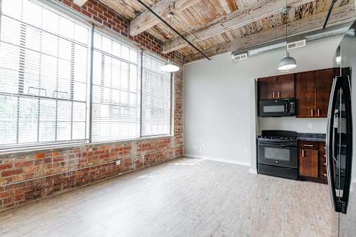 A kitchen area with a brick wall and wooden flooring at Spaulding Lofts Apartments, Grinnell, Iowa