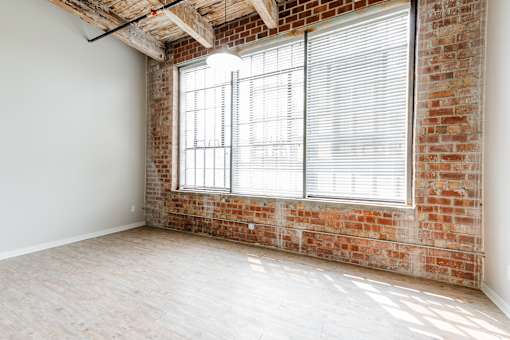A room with a large window and a brick wall.