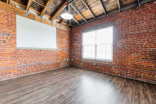 A room with a brick wall and wooden floor at Spaulding Lofts Apartments, Grinnell, Iowa