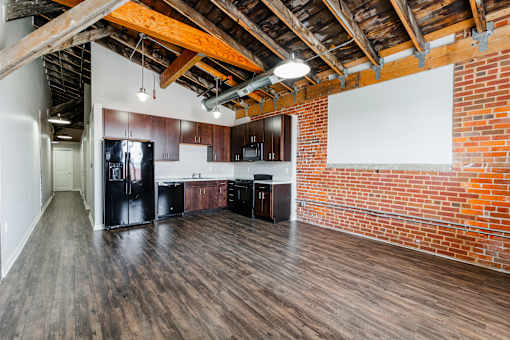 A kitchen area with wooden floors and a brick wall.