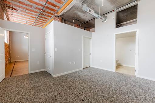 A room with white walls and a brick wall in the background.