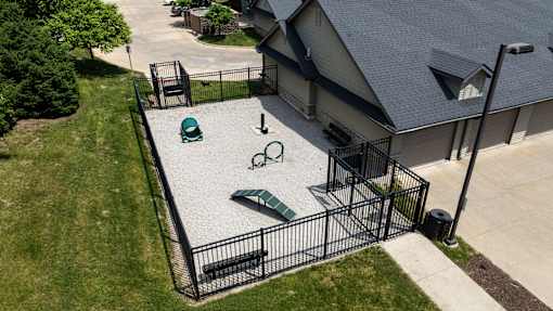 A black metal fence surrounds a green and white sandbox.