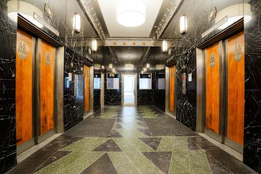 A long hallway with marble floors and wood doors.
