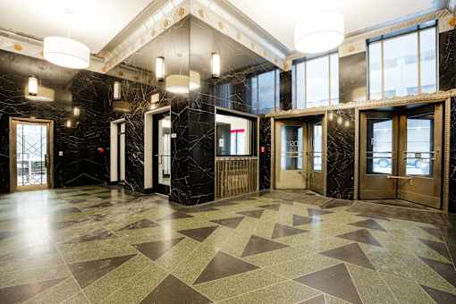 A hallway with marble floors and wooden doors.
