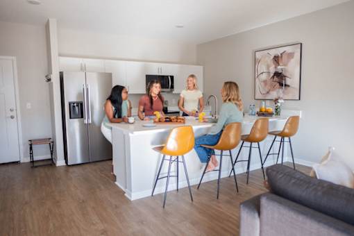 Four women are standing around a kitchen island.
