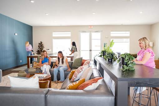 A group of people are sitting and standing in a room with a bar area.