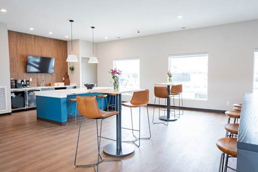 A modern kitchen with blue bar stools and a wooden counter.