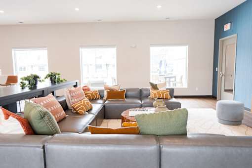 A living room with a grey couch and orange pillows.