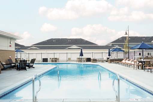 A large swimming pool with a diving board and lounge chairs.