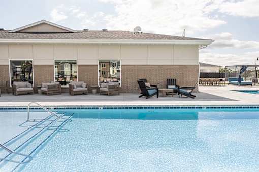 A swimming pool in front of a building with a white roof.