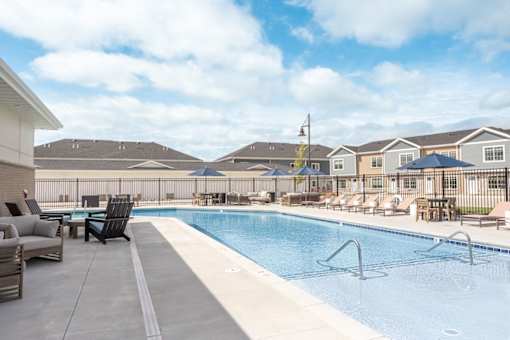 A swimming pool with a white fence and a blue sky in the background.