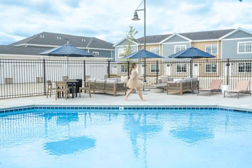 A woman is walking by a pool in a residential area.
