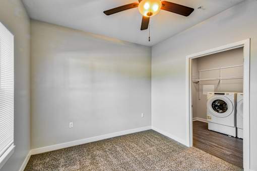 A room with a ceiling fan and a washing machine in it.