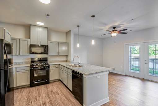 A kitchen with a refrigerator, oven, and sink.