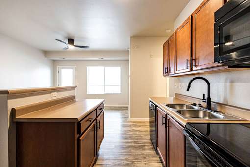 A kitchen with dark wood cabinets and a black stove top oven at Meadowlark Place Apartments, Iowa, 50111
