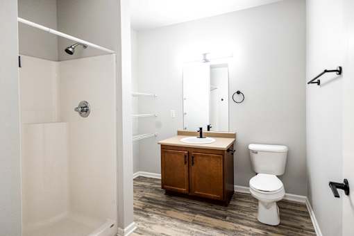 A bathroom with a toilet, sink, and shower at Meadowlark Place Apartments, Grimes, IA,  50111