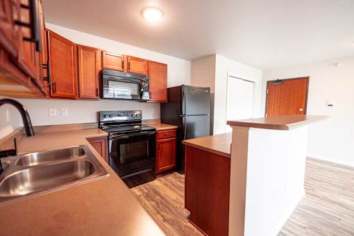 Kitchen with brown wooden cabinets at Meadowlark Place Apartments, Grimes, IA,  50111