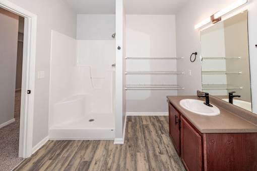 A bathroom with a white tub and wooden floors at Meadowlark Place Apartments, Grimes