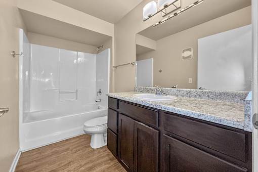 A bathroom with a toilet, sink, and shower at Melbourne Apartments in Des Moines, Iowa 50320.