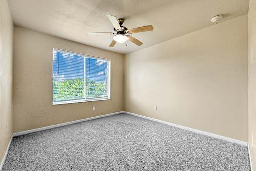 A room with a ceiling fan and a window.
