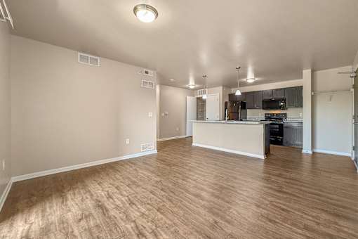 A spacious living room with wooden flooring and a kitchen area in the background at Melbourne Apartments in Des Moines, Iowa 50320.