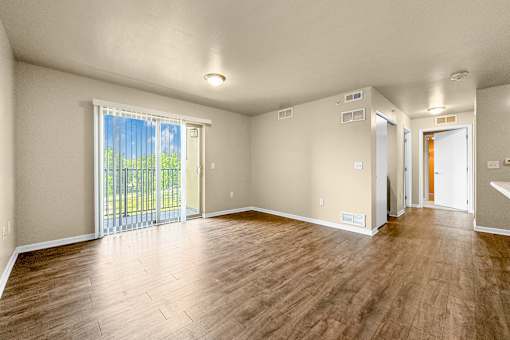 A room with wooden flooring and sliding glass doors at Melbourne Apartments in Des Moines, Iowa 50320.