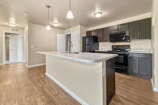 A kitchen with a marble countertop and black appliances at Melbourne Apartments in Des Moines, Iowa 50320.
