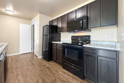 A kitchen with black appliances and wooden floors at Melbourne Apartments in Des Moines, Iowa 50320.