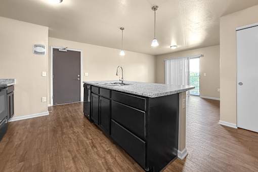 A kitchen at Melbourne Apartments in Des Moines, Iowa 50320 with black cabinets and hardwood flooring.