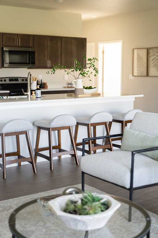 a view of a kitchen with bar stools and a living room with a counter at Converge NW, Waukee Iowa  