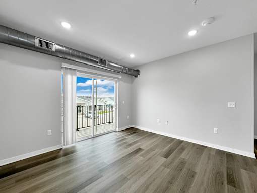 an empty living room with a sliding glass door to a balcony at Converge NW, Waukee  