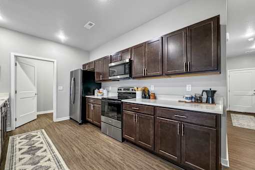 a kitchen with dark wood cabinets and a stainless steel refrigerator at Converge NW, Iowa  