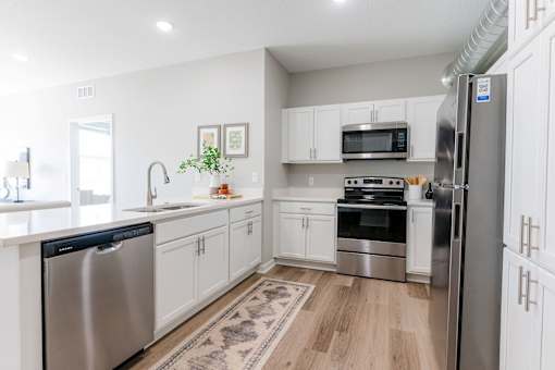 A kitchen with white cabinets and stainless steel appliances at Converge NW, Waukee, IA