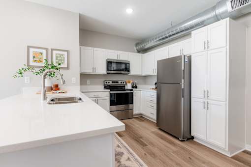 A kitchen with white cabinets and a stainless steel refrigerator.at Converge NW, Waukee, IA 50263  