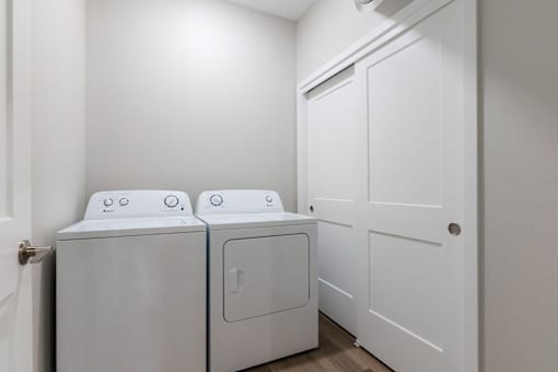 Two white front loading washing machines in a laundry room.at Converge NW, Iowa  