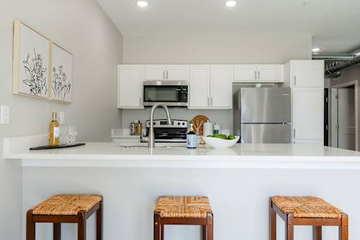 a kitchen with a counter top and stools at Converge NW, Waukee, IA  
