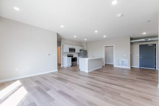 the living room and kitchen of a new home with white walls and wood flooring at Converge NW, Waukee, 50263  