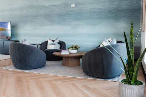 a living room with blue furniture and a blue wall and wood floors at Converge NW, Waukee, 50263  